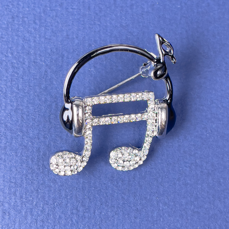Brooch 'Note in Headphones' with white crystals on black enamel, silver metal 27x32mm+